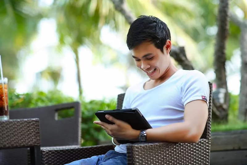seorang pria memainkan tablet sambil tersenyum