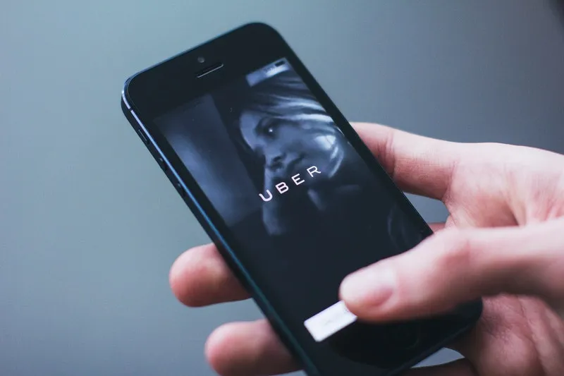 seseorang membuka aplikasi ojol uber di handphone