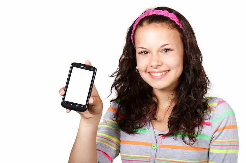 seorang wanita tersenyum sambil menunjukkan layar handphone