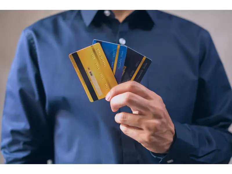 seseorang sedang memegang tiga kartu kredit