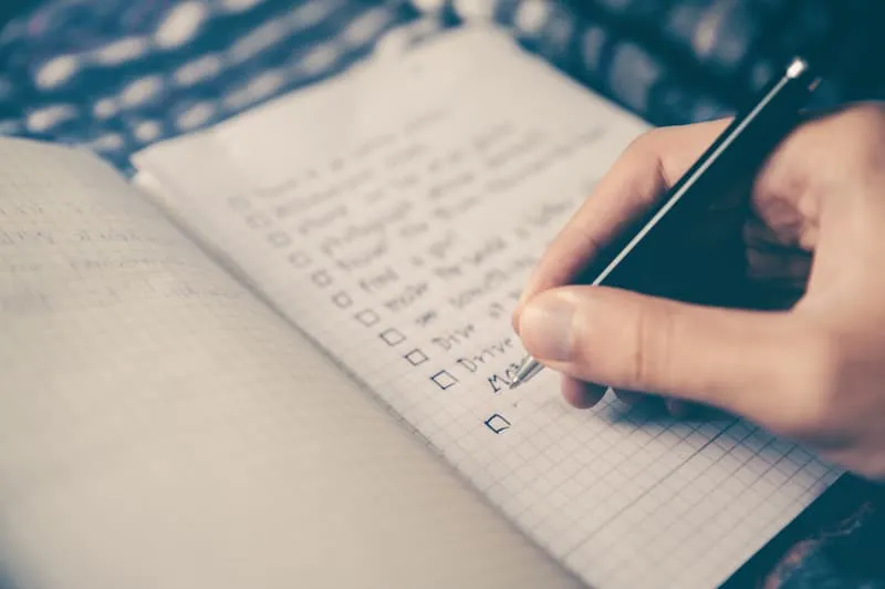 seseorang sedang menandai checklist di buku catatan