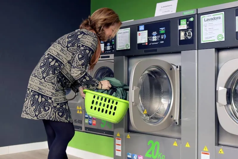 seorang wanita sedang memasukkan cucian ke mesin laundry