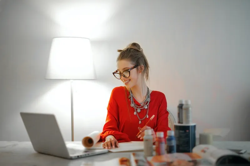 seorang wanita bekerja sambil tersenyum di depan laptop