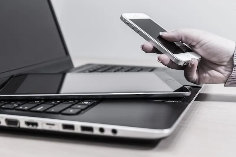 seseorang menggunakan handphone di depan laptop