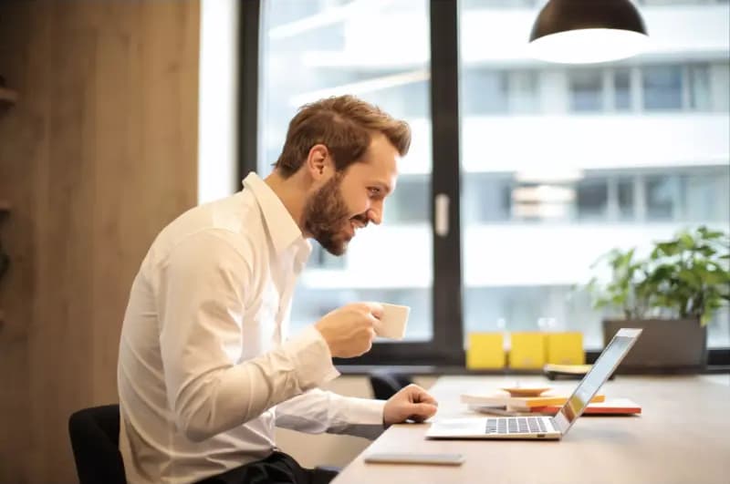 seorang pria bekerja sambil tersenyum di depan laptop