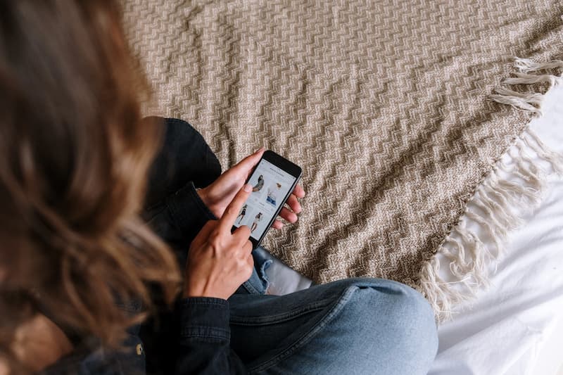 seorang wanita sedang membuka halaman toko online di handphone