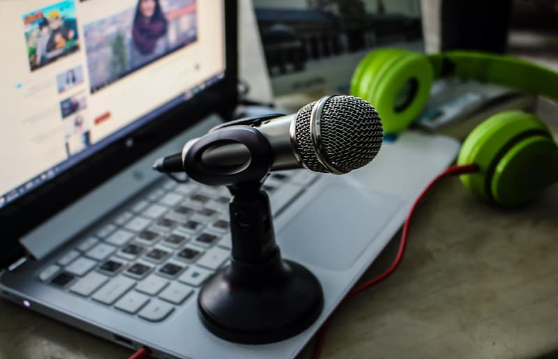 sebuah mic di atas laptop sebagai alat podcaster