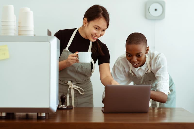 dua orang wanita sedang menatap layar laptop