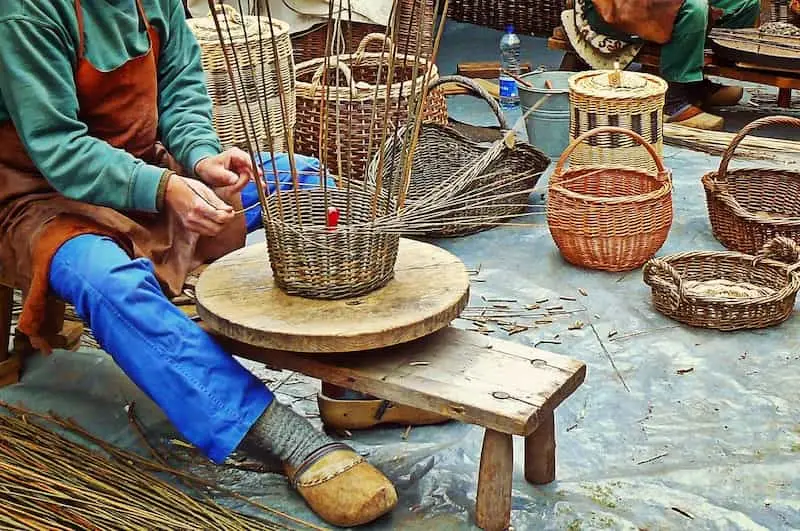 seseorang sedang menganyam keranjang dari bambu